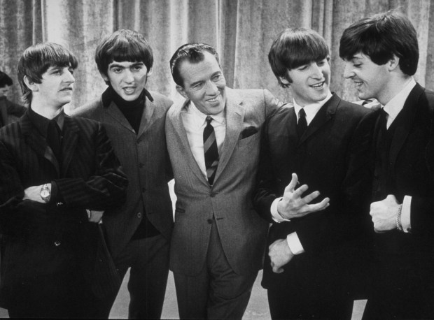 American television host Ed Sullivan (center) smiles as he stands, with the members of British rock group the Beatles, on the set of his television variety series, 'The Ed Sullivan Show' at CBS's Studio 50, New York, New York, February 9, 1964. Pictured are, from left, Ringo Starr, George Harrison, Sullivan, John Lennon, and Paul McCartney. The photo was taken during prior to the group's debut performance on the show later that day. (Photo by Express Newspapers/Getty Images)