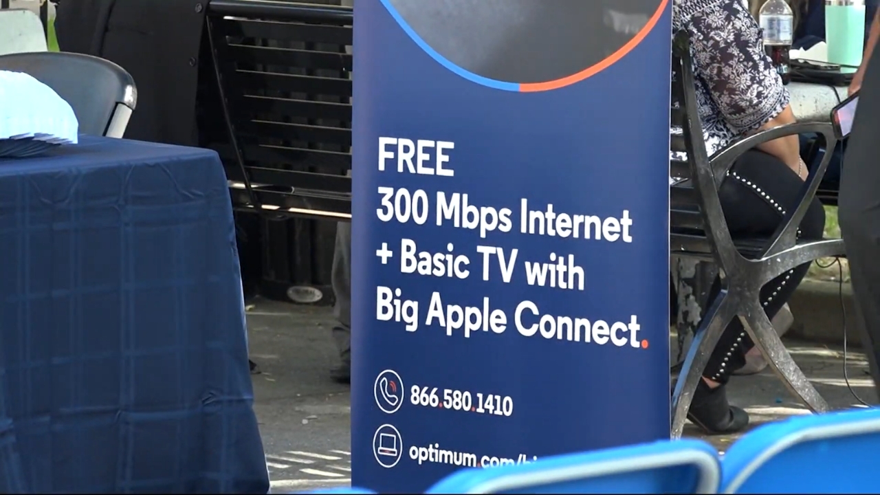 Big Apple Connect sign advertises free internet and basic TV service at a public outreach table
