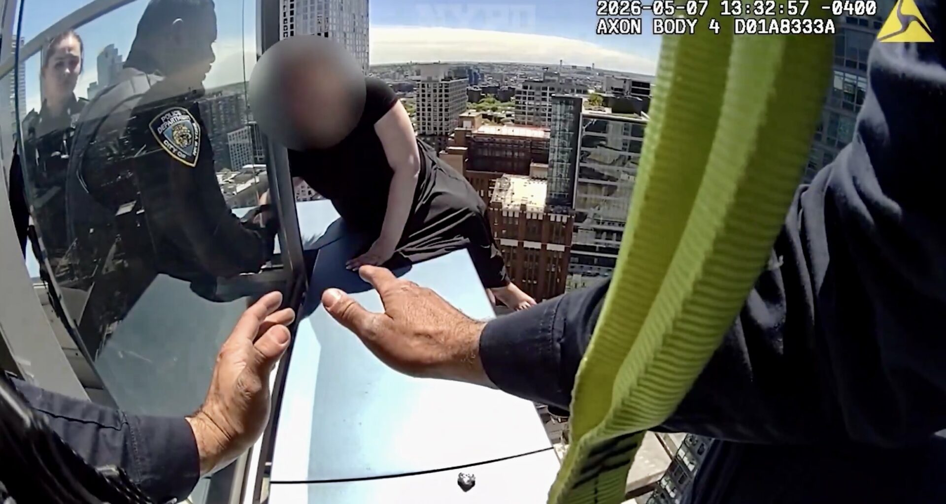 While Officer Nicholas holds her hand, a member of NYPD’s Emergency Services Unit climbs out onto the ledge and tells the woman, “I’m here now.” Photo: NYPD video