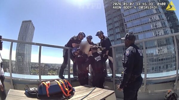 Members of NYPD’s Emergency Services Unit lift the woman over the glass barrier. Photo: NYPD video