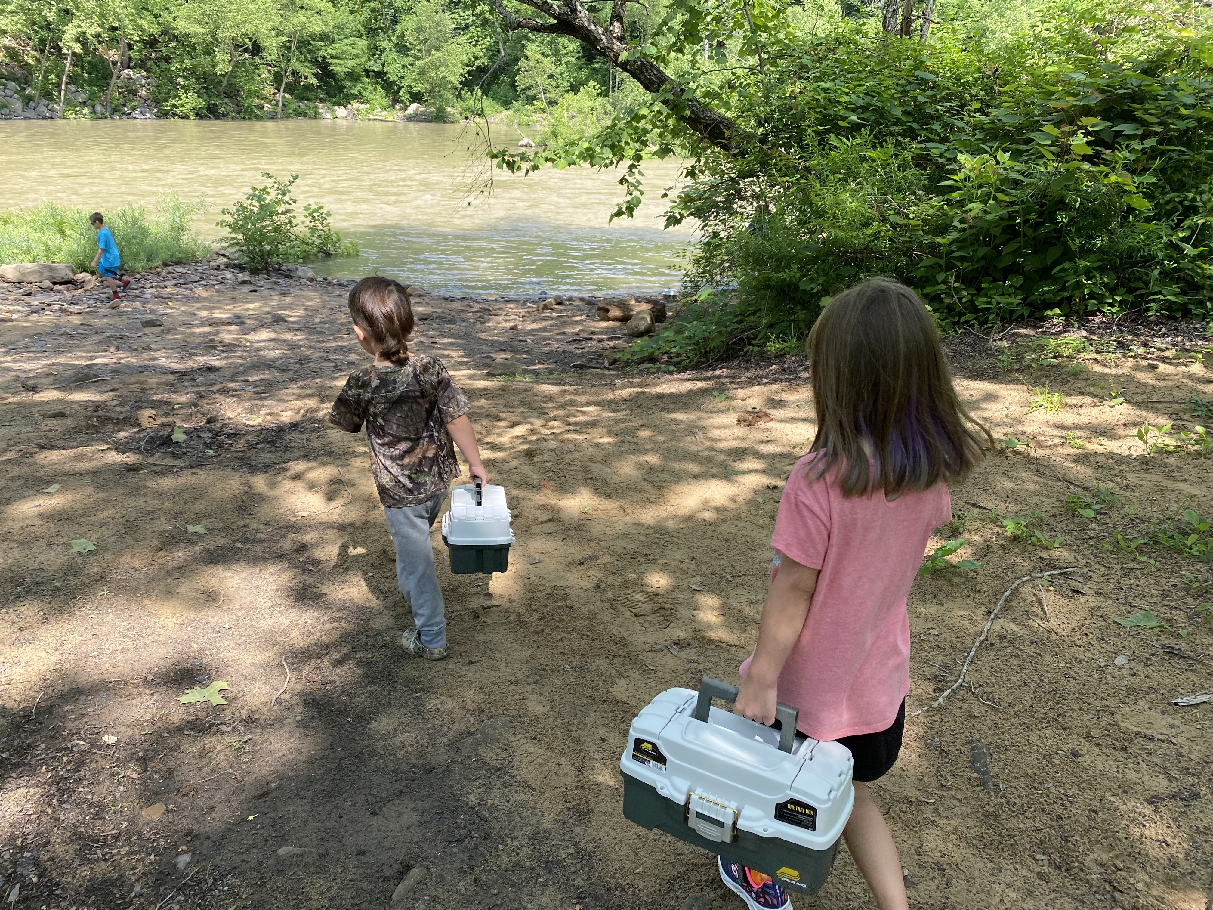 Kids Fishing two children carrying tackle boxes walk toward a river