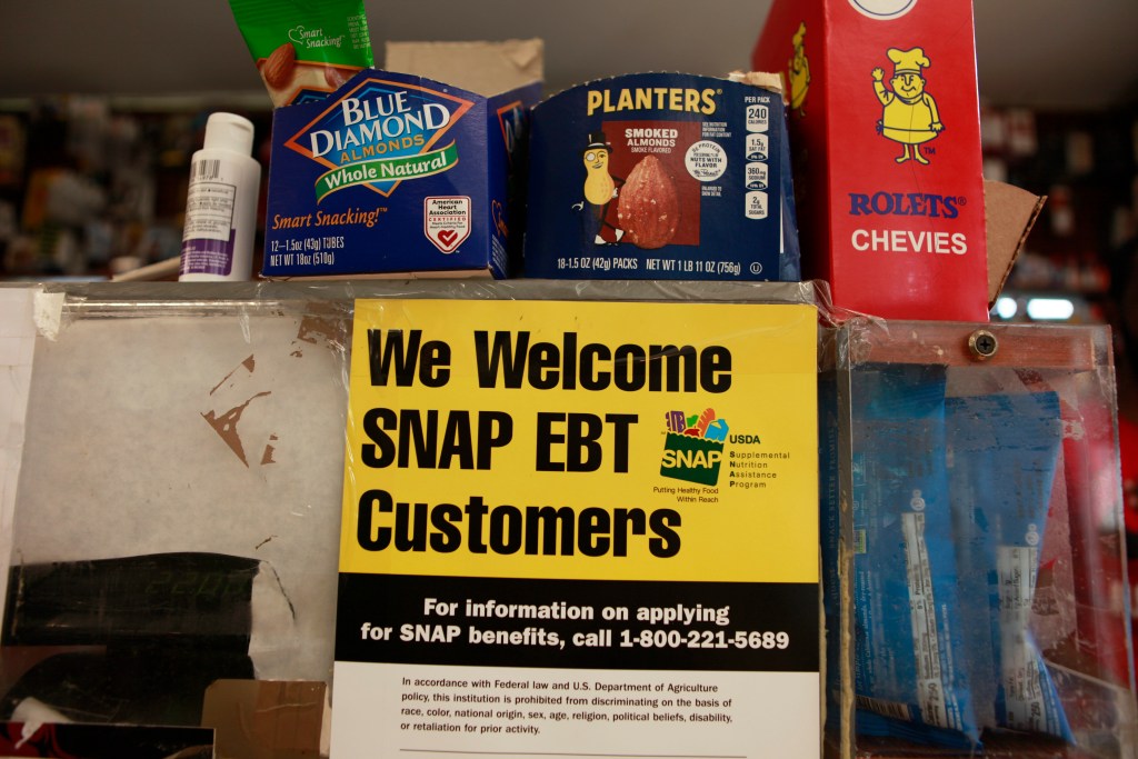 A yellow and black sign in a Crown Heights bodega reads: "We Welcome SNAP EBT Customers."