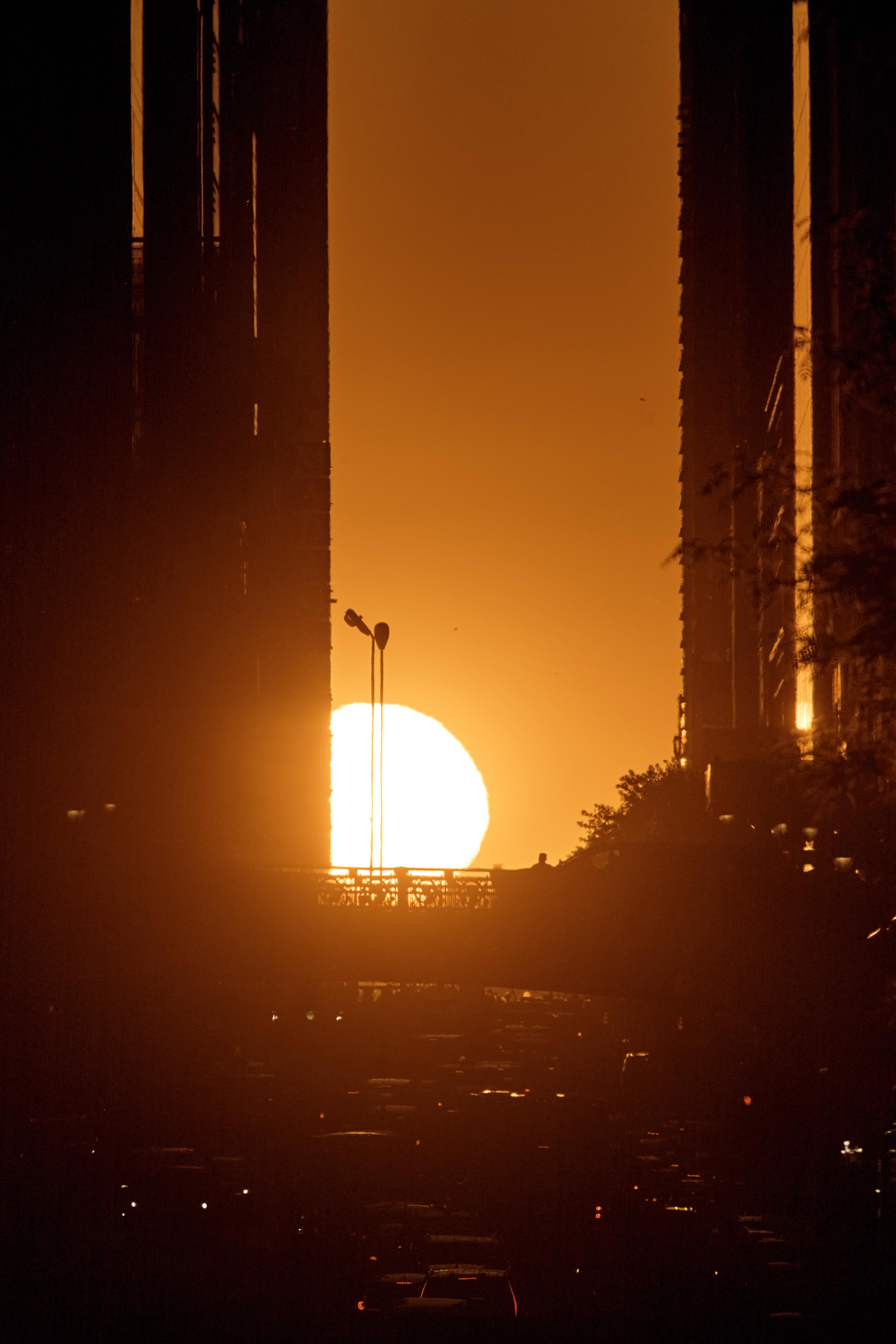 The setting sun is framed between buildings during Manhattanhenge.