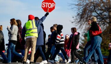 crossing guard holds up stop sign as students cross street