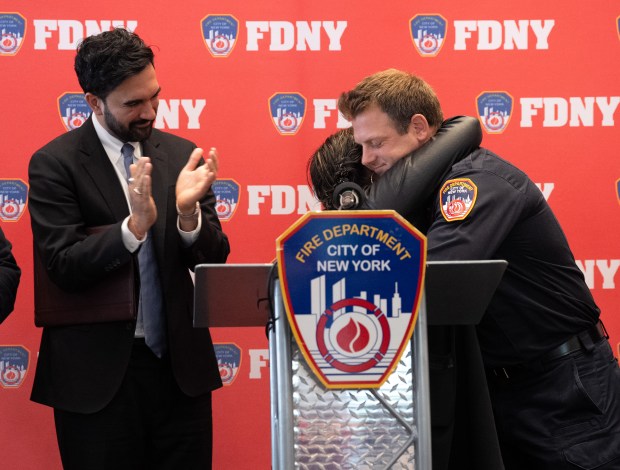 FDNY firefighter Travis Langan hugs Carmen Pinto as Mayor Zohran Mamdani applauds at FDNY headquarters Friday, May 22, 2026 in Brooklyn, New York. Langan rescued Pinto in flood waters on Wednesday. (Barry Williams/ New York Daily News)
