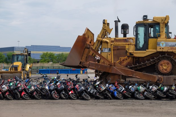 A bulldozer crushes a pile of seized illegal scooters and motorcycles at a DSNY facility in Staten Island, New York on Wednesday, May 13, 2026. (Gardiner Anderson / New York Daily News)