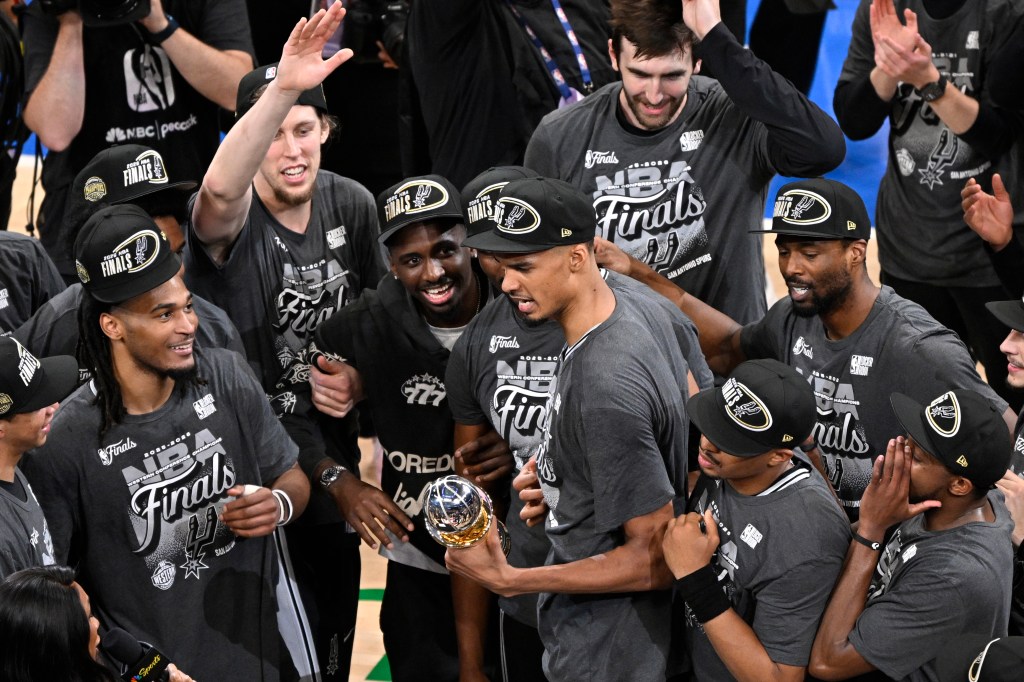 Victor Wembanyama, holding the Western Conference MVP trophy he won, celebrates with teammates after the Spurs' 111-103 Game 7 win over the Thunder on May 30, 2026 in Oklahoma City.