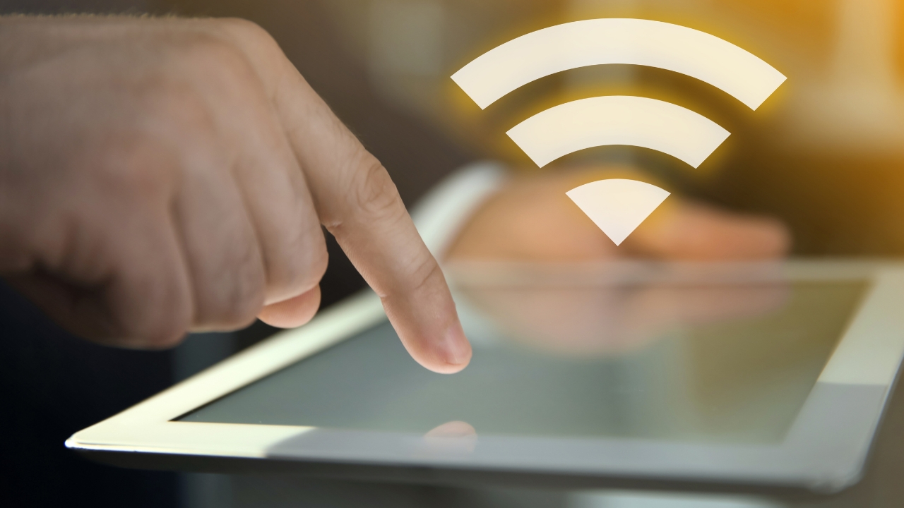 A person taps a tablet screen with a Wi-Fi symbol above it