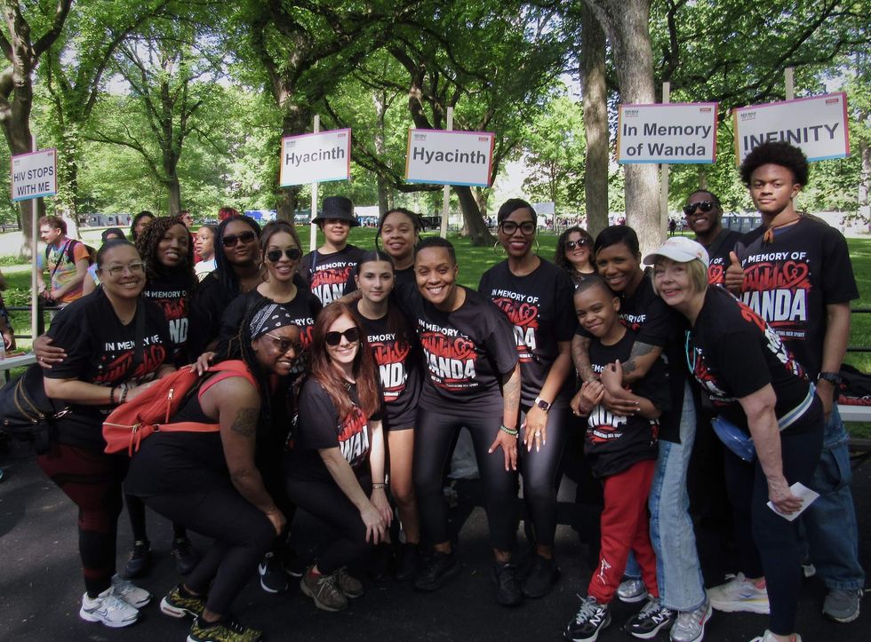 A group of people in black and red shirts crowd in front of a table with a sign that reads "In Memory of Wanda."