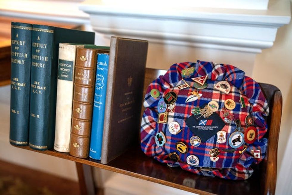 A pin cushion covered in pin badges sitting on a mantlepiece