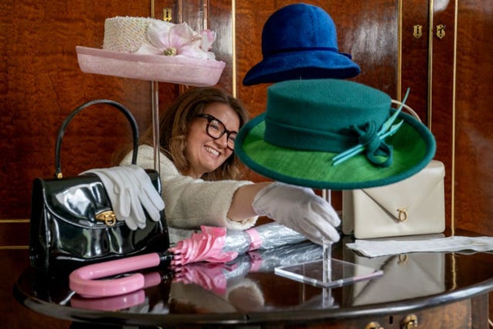 A woman adjusts an item of the Queen's belongings on display
