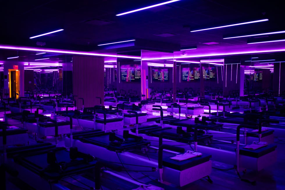 Fitness studio featuring reformer machines and neon lighting.