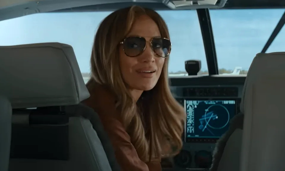 Jennifer Lopez sits in the pilot seat of a plane in her newest rom-com Office Romance.