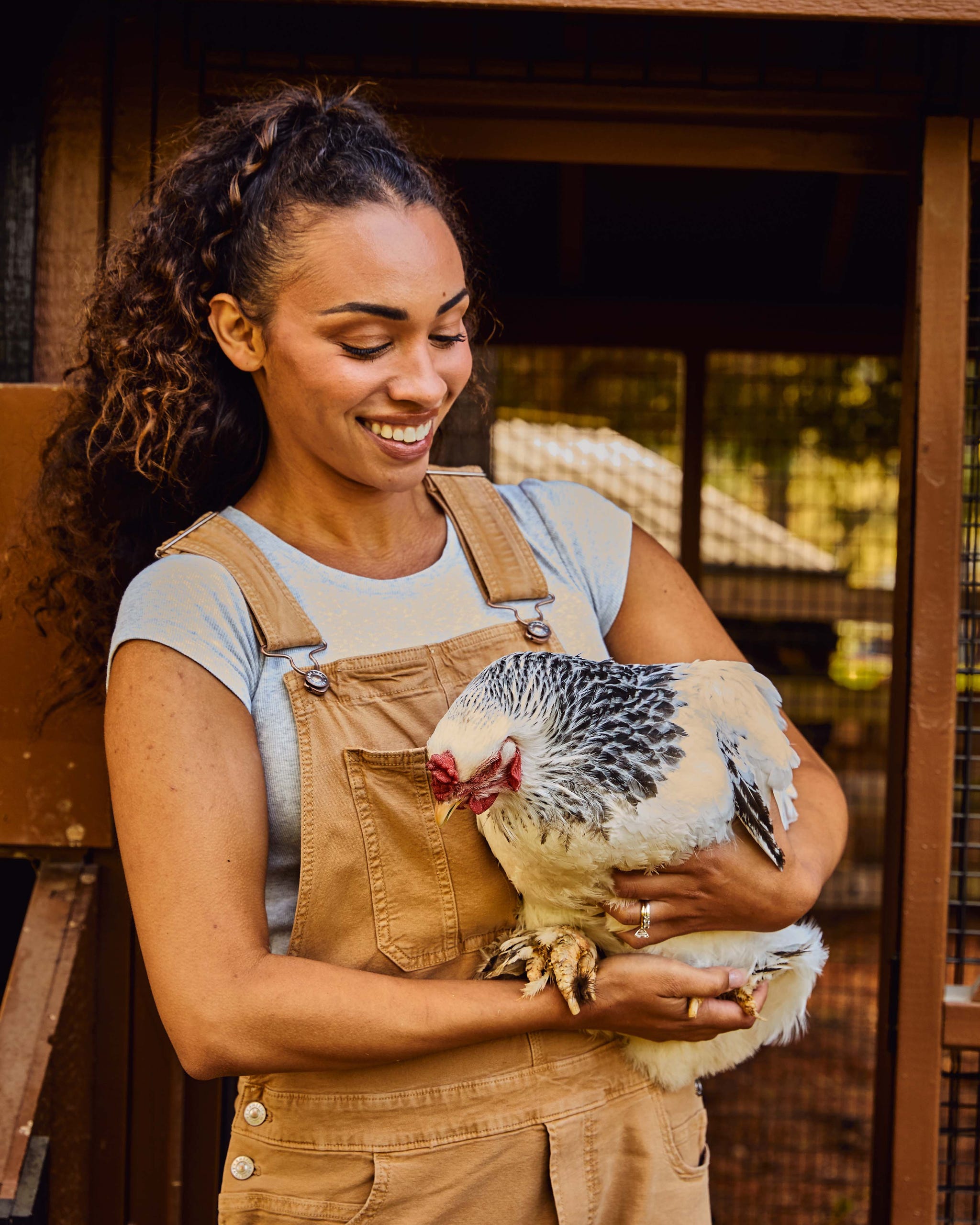 Person holding a chicken in a farm setting.
