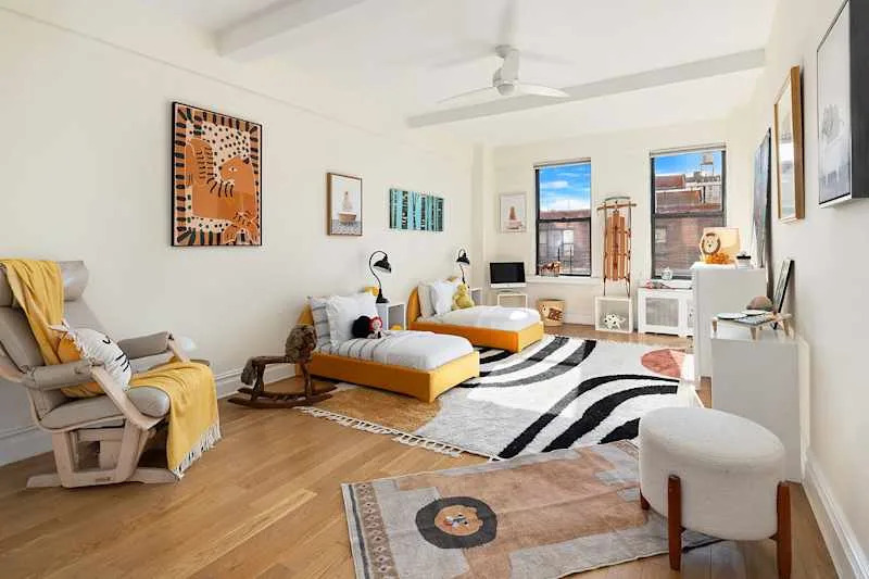 Bright children's room featuring two yellow beds, playful decor, a rocking horse, and colorful artwork on the walls.