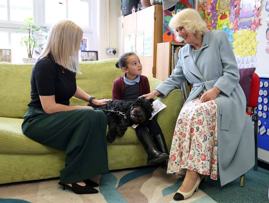 Britain's Queen Camilla meets five-year-old Tawnie, and Tilly the dog, during a visit Fane Street Primary School in Belfast, Northern Ireland on May 19, 2026, during her three-day visit with Britain's King Charles III to Northern Ireland