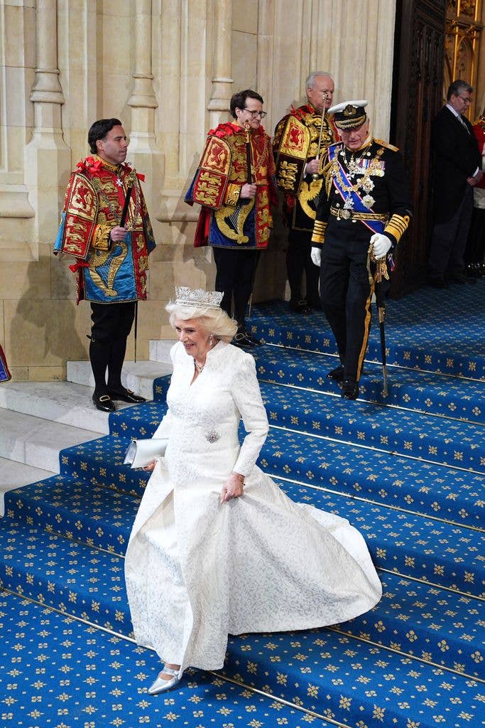 Queen Camilla going down steps in white dress