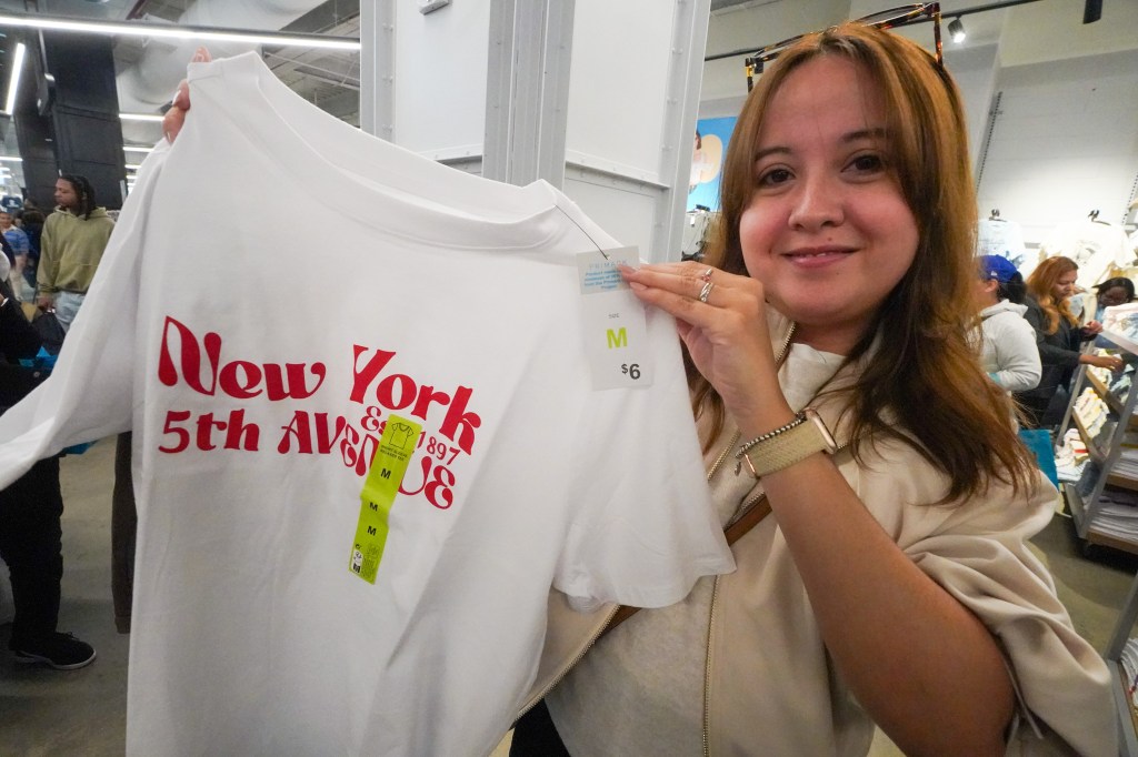 Beatriz Velanova holds up a white Primark t-shirt with "New York 5th Avenue" printed in red, priced at $6.