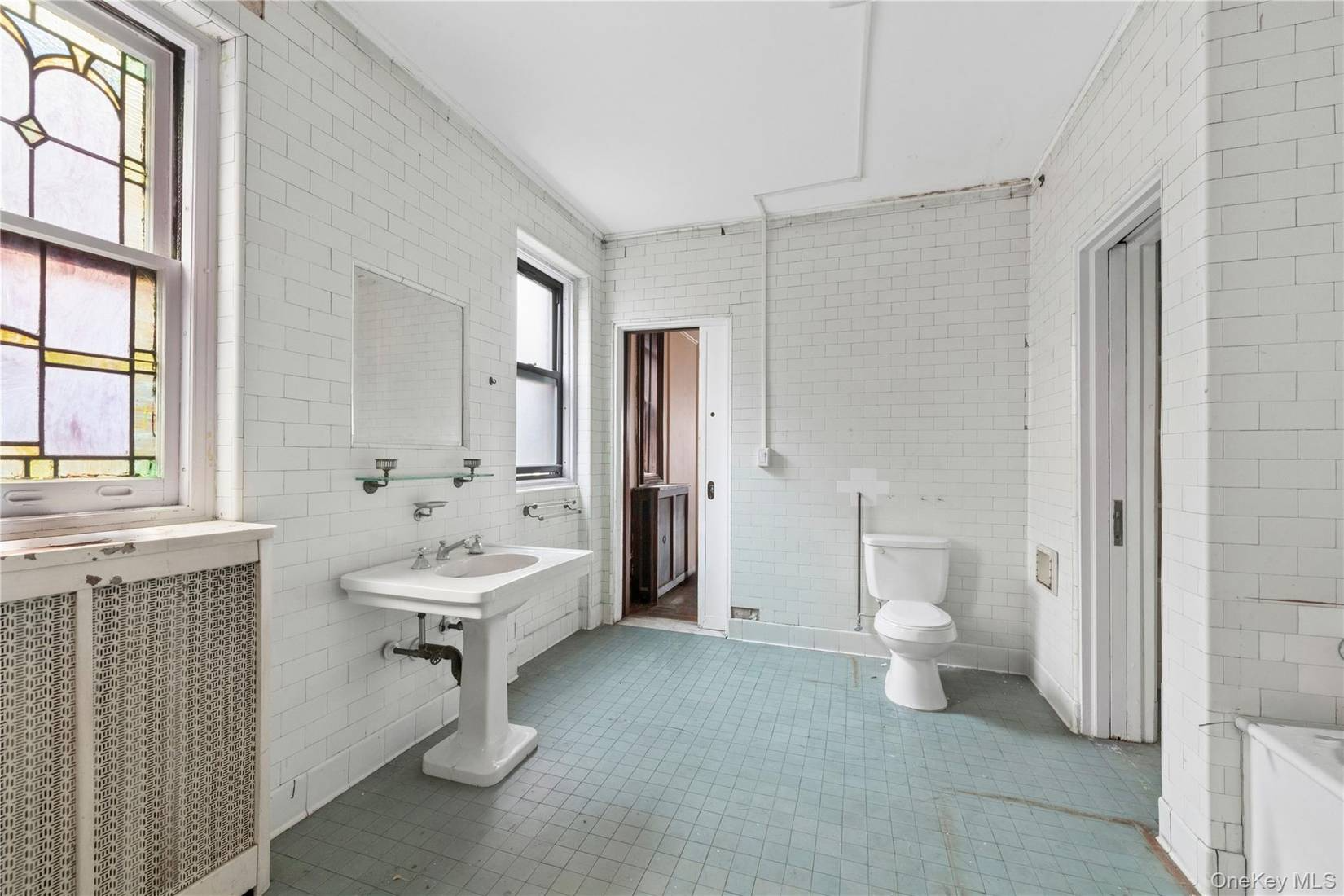 bathroom with white subway tile on walls, a stained glass window