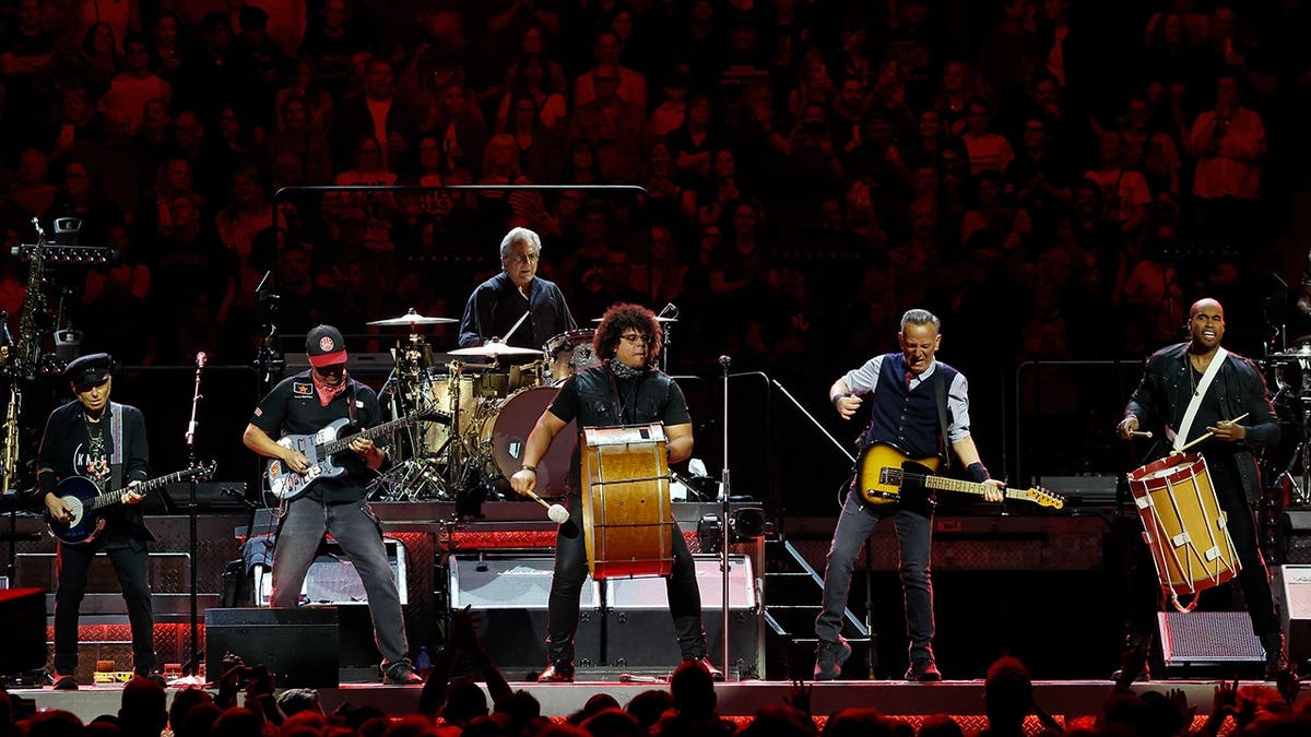 Bruce Springsteen performing with Nils Lofgren, Tom Morello, Max Weinberg, Jake Clemons, and Anthony Almonte on stage
