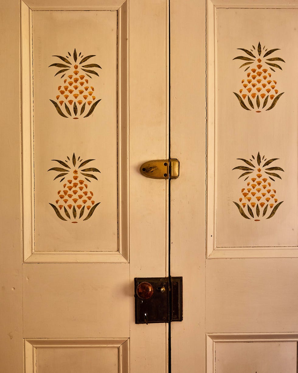 Decorative double doors featuring pineapple motifs and a locking mechanism.