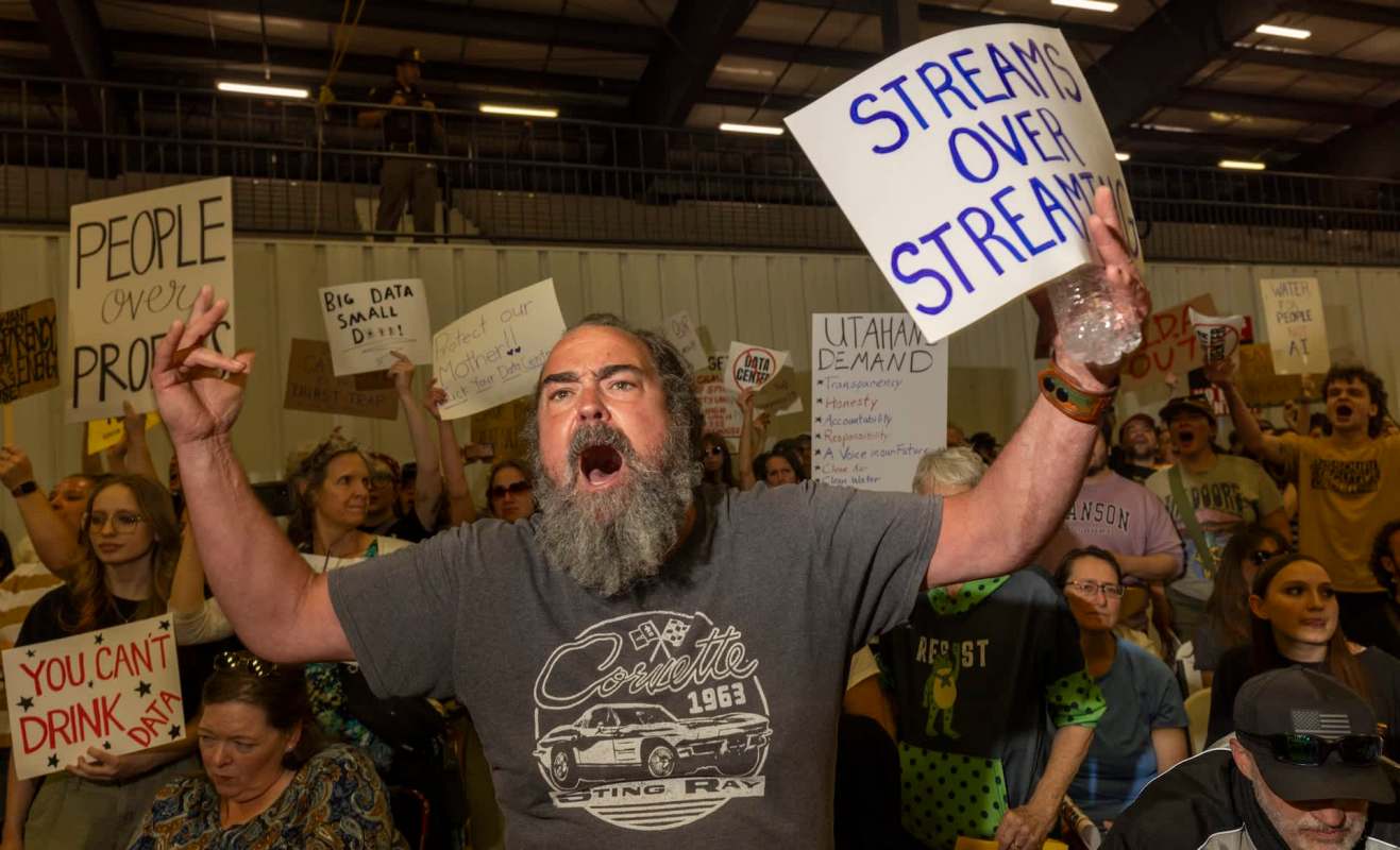 A passionate protestor shouts with a sign demanding water rights amid a crowd holding various protest signs.