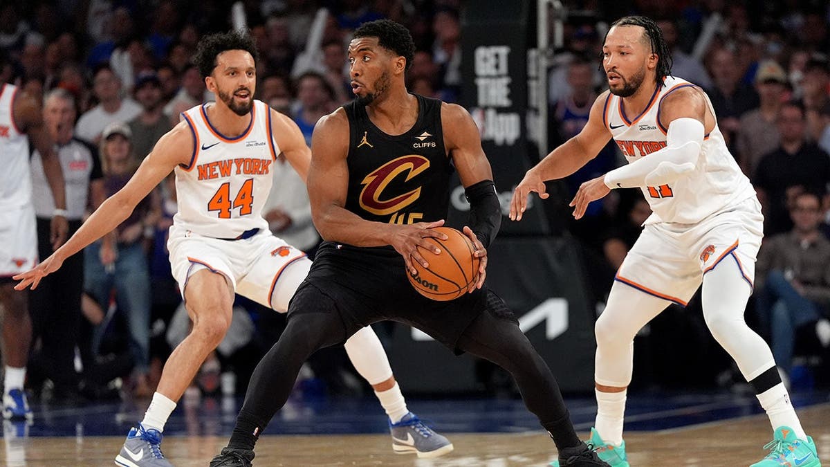 Donovan Mitchell dribbling basketball defended by Landry Shamet and Jalen Brunson in a game