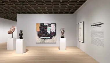 Art gallery interior featuring sculptures and paintings on display with white walls and a wooden floor.
