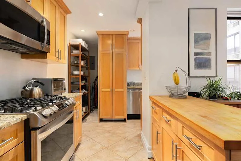 Modern kitchen with wooden cabinets, stainless steel appliances, a gas stove, and a countertop with a fruit bowl.