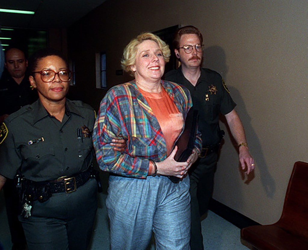 Betty Broderick, handcuffed and smiling, escorted by two marshals after her murder conviction.