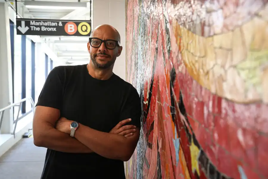 artist posing next to mosaic