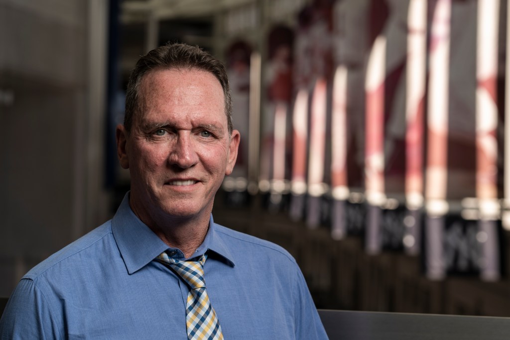 David Cone, former New York Yankees pitcher and current YES Network commentator, smiling while wearing a blue shirt and plaid tie.