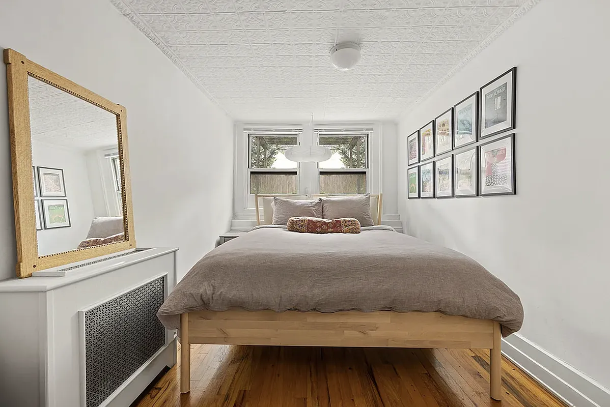 bedroom with tin ceiling, wood floor, white walls