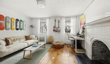 living room with white walls, white mantel, wide planked floorboards