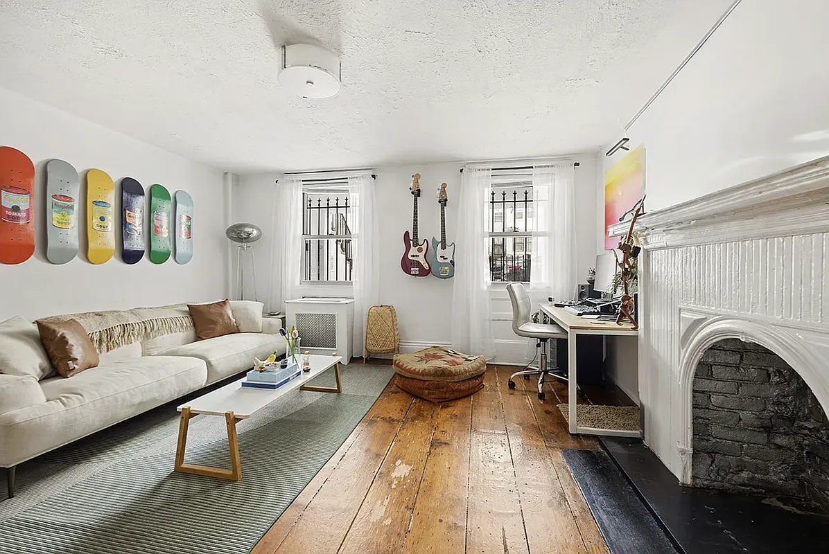living room with white walls, white mantel, wide planked floorboards