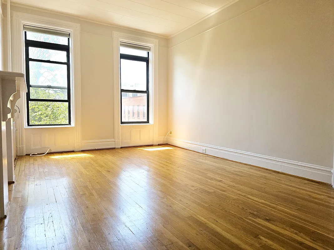 front room with window moldings, mantel, and wood floor