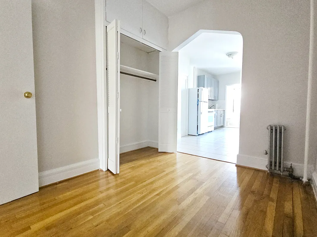 room with closet, arched doorway to kitchen