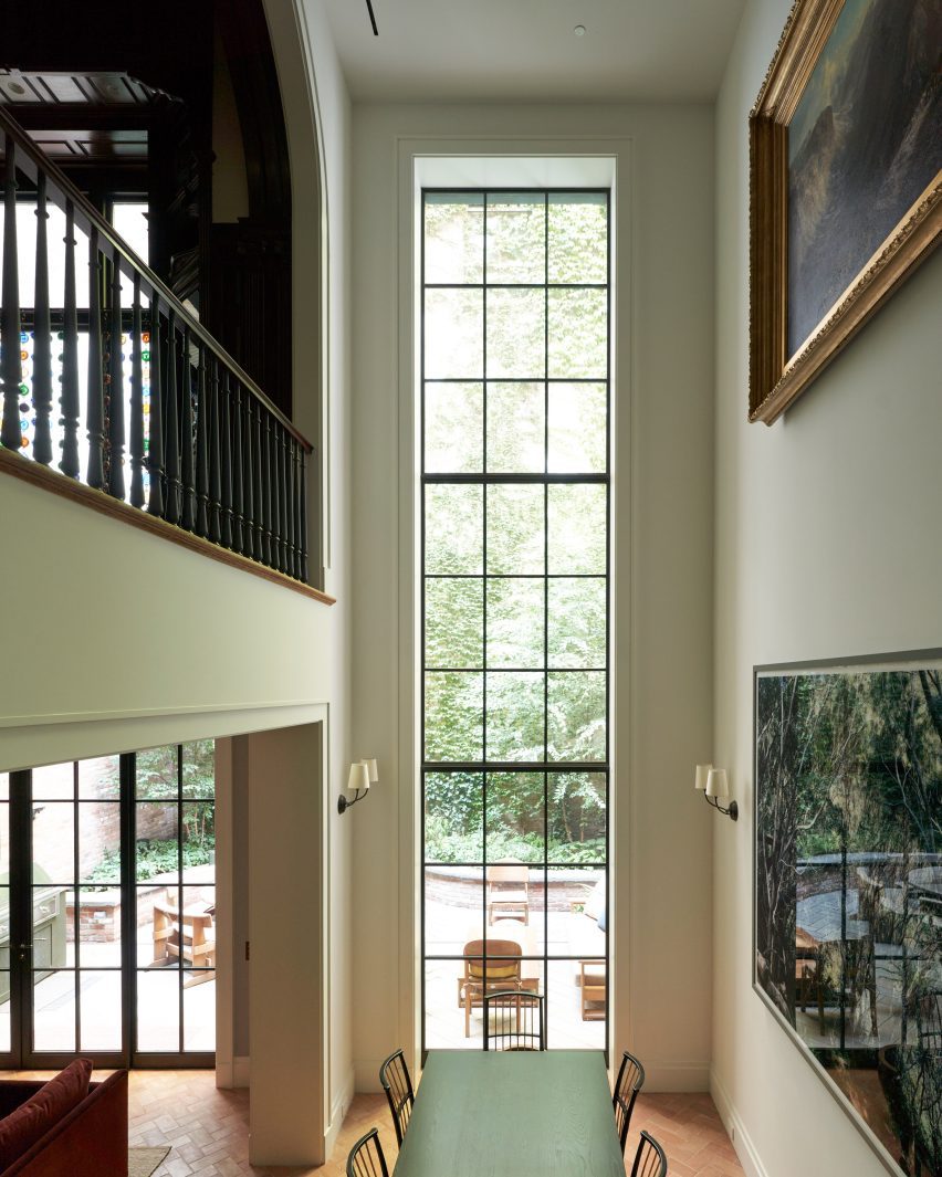 A double-height atrium with a tall window overlooking a garden