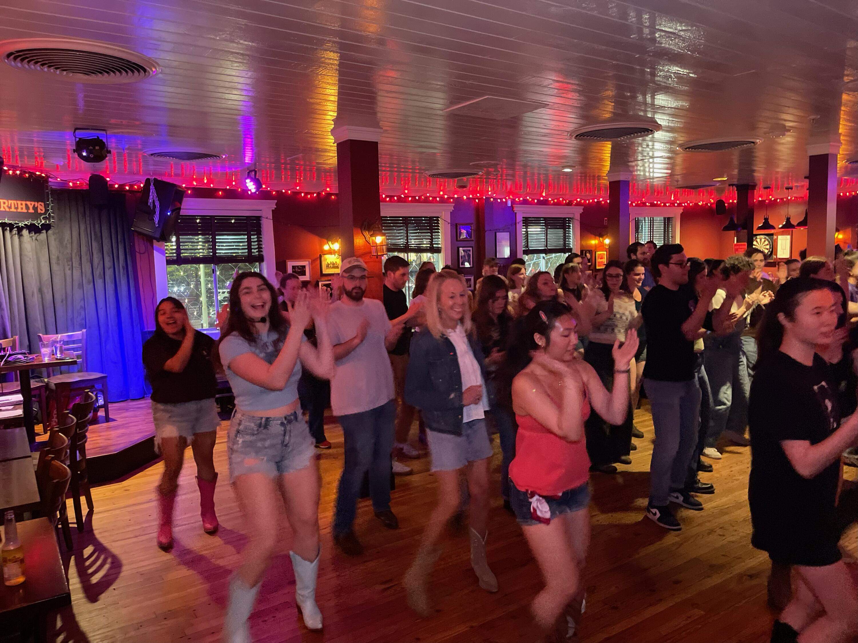 Albert and Falso (left) dance alongside guests at a line dancing event. (Courtesy Line Dancing Queens)