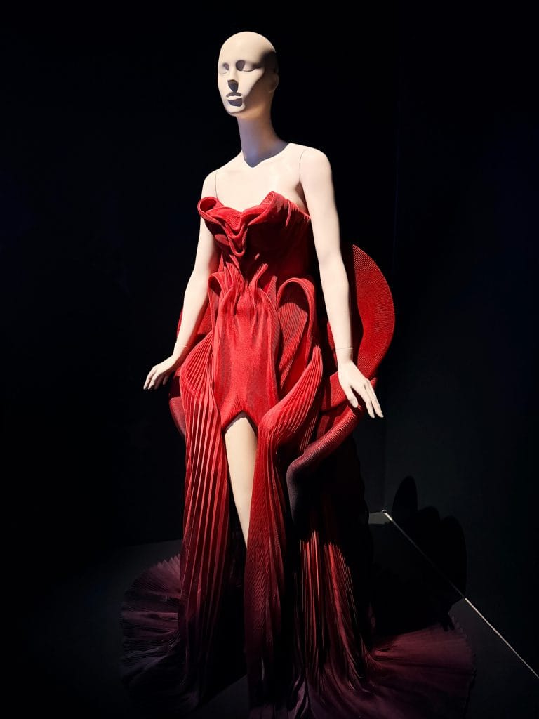 A structured red dress seen on a mannequin