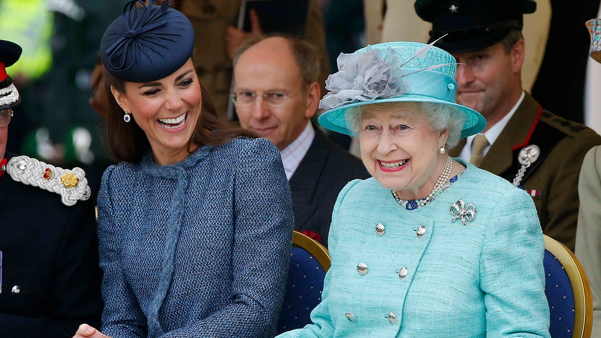 Catherine Duchess of Cambridge and Queen Elizabeth II watching a children's sports event in a park