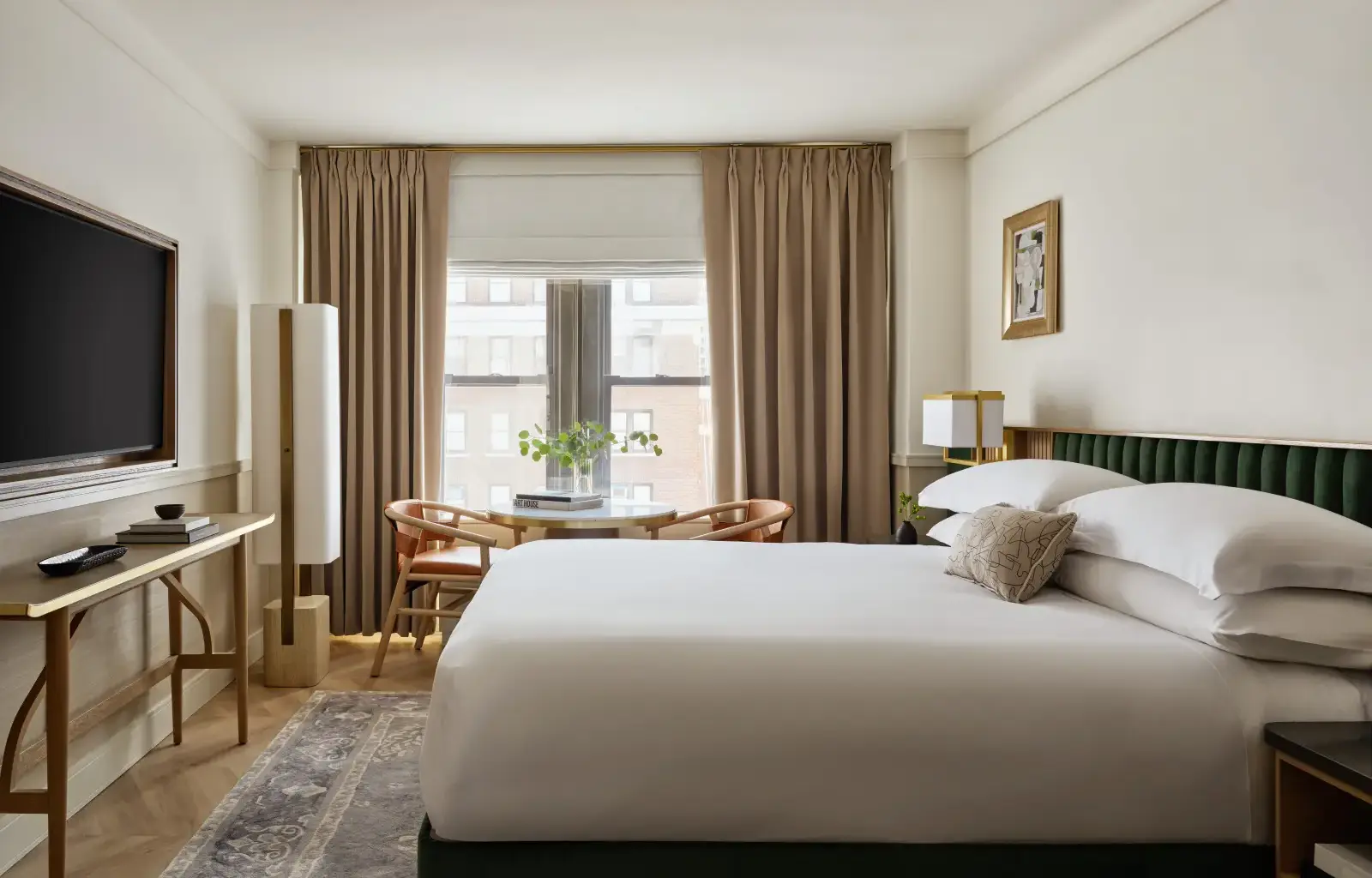 Modern guest room at Kimpton Ashbel New York with king bed, city-view window, soft neutral decor and seating area.