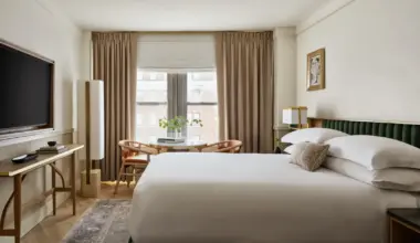 Modern guest room at Kimpton Ashbel New York with king bed, city-view window, soft neutral decor and seating area.