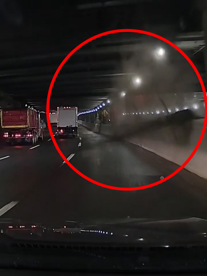 Debris falling from the ceiling of a tunnel, with two trucks driving ahead.