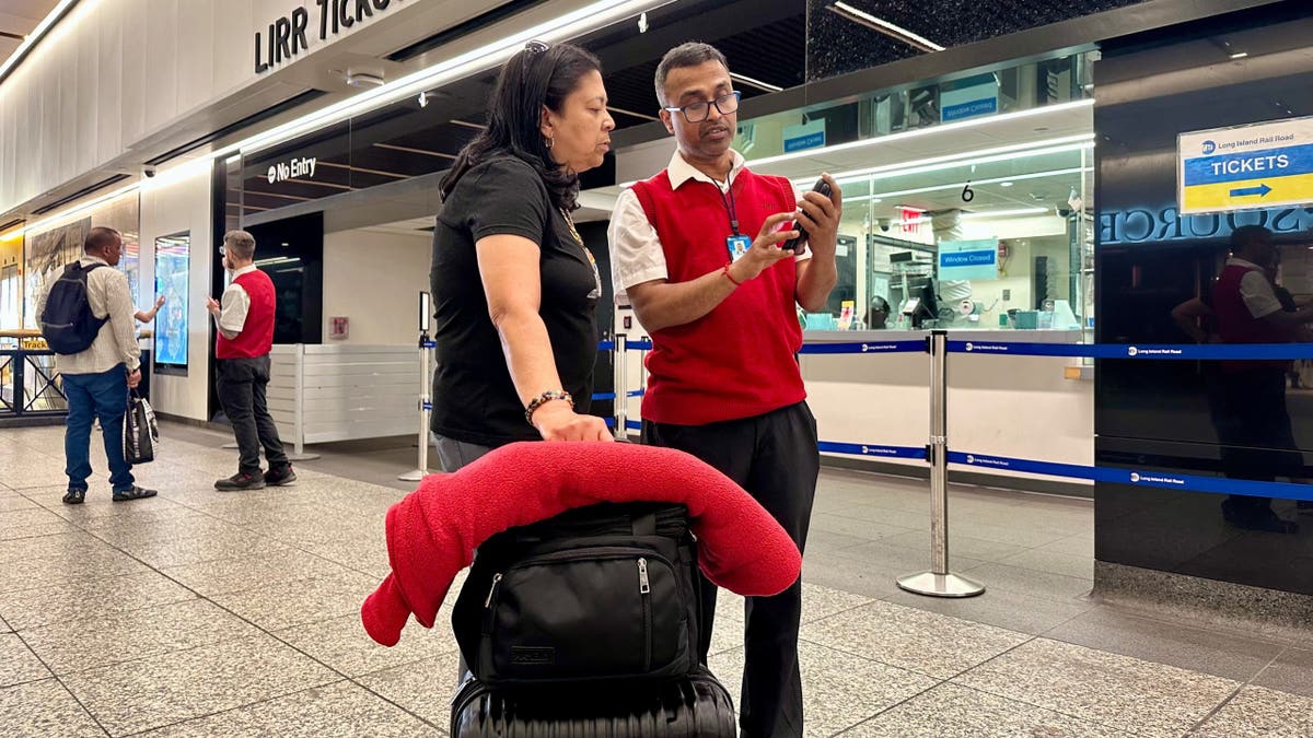Long Island Rail Road employee Sujit Saha helping a passenger at Penn Station in New York