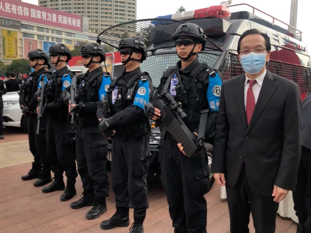 Harry Lu, a Chinatown community leader and alleged Chinese spy, stands next to armed police officers.
