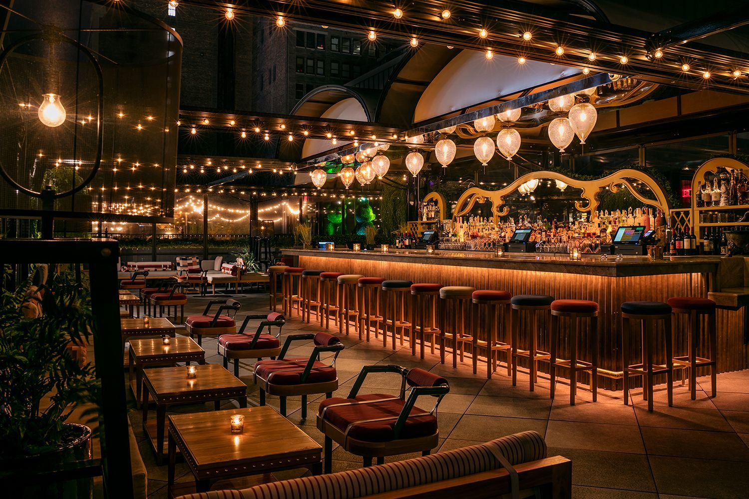 Illuminated bar and lounge seating under string lights at the outdoor East Patio of Magic Hour Rooftop Bar in Moxy Times Square.
