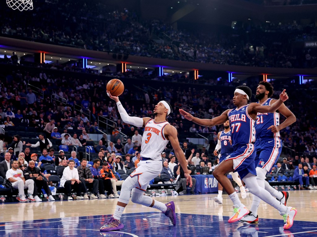 New York Knicks guard Josh Hart #3 drives to the basket as Philadelphia 76ers guard Vj Edgecombe #77 and center Joel Embiid #21 give chase during an NBA Playoffs game.