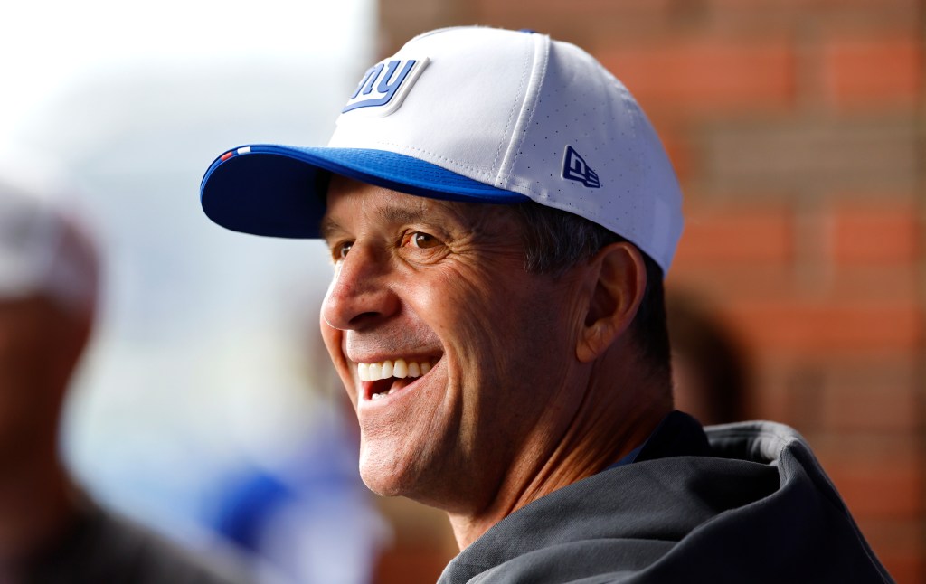 New York Giants head coach John Harbaugh smiling during football practice.