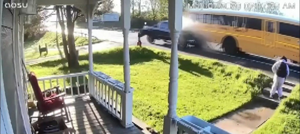 A blue pickup truck crashes into the back of a school bus